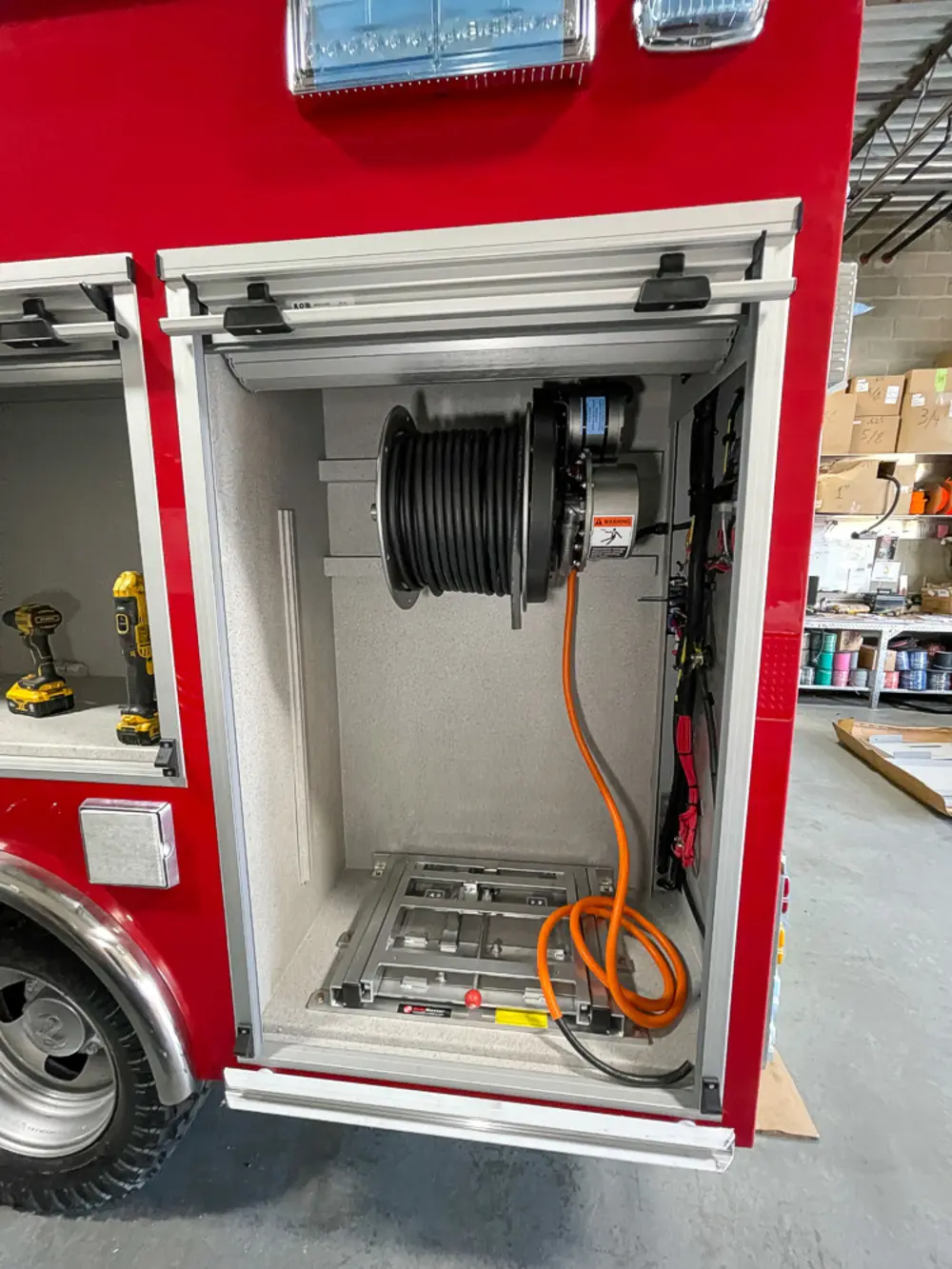 Exterior view of small fire truck showing cab, body compartments, and wheel/tire area.